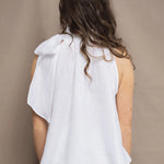 a woman wears an Irish linen halter top with bow detailing on the shoulder in white with matching white linen trousers 