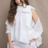 a woman wears an Irish linen halter top with bow detailing on the shoulder in white with matching white linen trousers and white cashmere wrap shawl in white