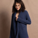 A woman wears a long cashmere cardigan in inky blue colour over bright pink silk trousers