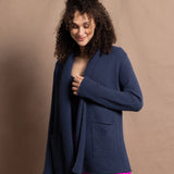 A woman wears a long cashmere cardigan in inky blue colour over bright pink silk trousers