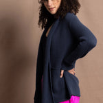 A woman wears a long cashmere cardigan in inky blue colour over bright pink silk trousers