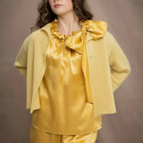 a woman wears a pure 100% cashmere cropped cardigan sweater in butter yellow over silk clothing in butter yellow