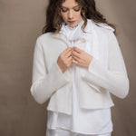 a woman wears an Irish linen halter top with bow detailing on the shoulder in white with matching white linen trousers with cropped cashmere cardigan over top in almost white