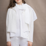a woman wears a pure 100% cropped cashmere cardigan over an irish linen halter shirt in white