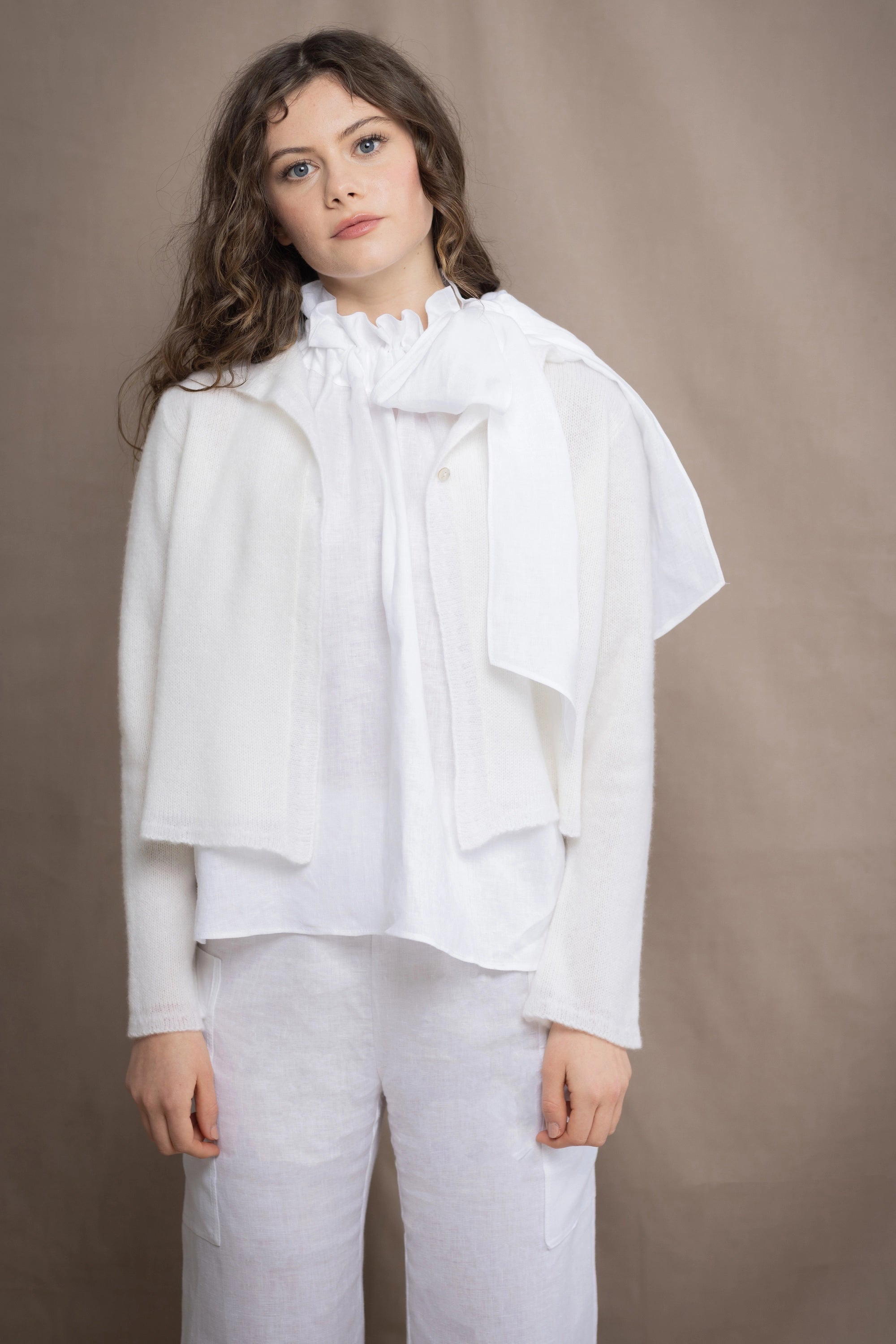 a woman wears a pure 100% cropped cashmere cardigan over an irish linen halter shirt in white