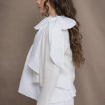 a woman wears a pure 100% cropped cashmere cardigan over an irish linen shirt in white