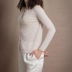 a woman wears a thin summer weight cashmere cardigan sweater in a cream colour with white silk shorts