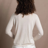 a woman wears a thin summer weight cashmere cardigan sweater in a cream colour with white silk shorts
