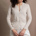 a woman wears a thin summer weight cashmere  button down cardigan sweater in a cream colour with white silk shorts