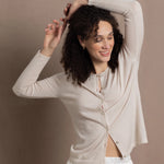 a woman wears a thin summer weight cashmere  button down cardigan sweater in a cream colour with white silk shorts