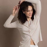 a woman wears a thin summer weight cashmere  button down cardigan sweater in a cream colour with white silk shorts