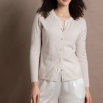 a woman wears a thin summer weight cashmere  button down cardigan sweater in a cream colour with white silk shorts