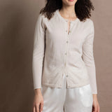 a woman wears a thin summer weight cashmere  button down cardigan sweater in a cream colour with white silk shorts