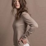 a woman wears a v neck thin summer weight cashmere sweater in a taupe colour and white jeans