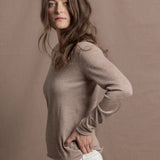 a woman wears a v neck thin summer weight cashmere sweater in a taupe colour and white jeans