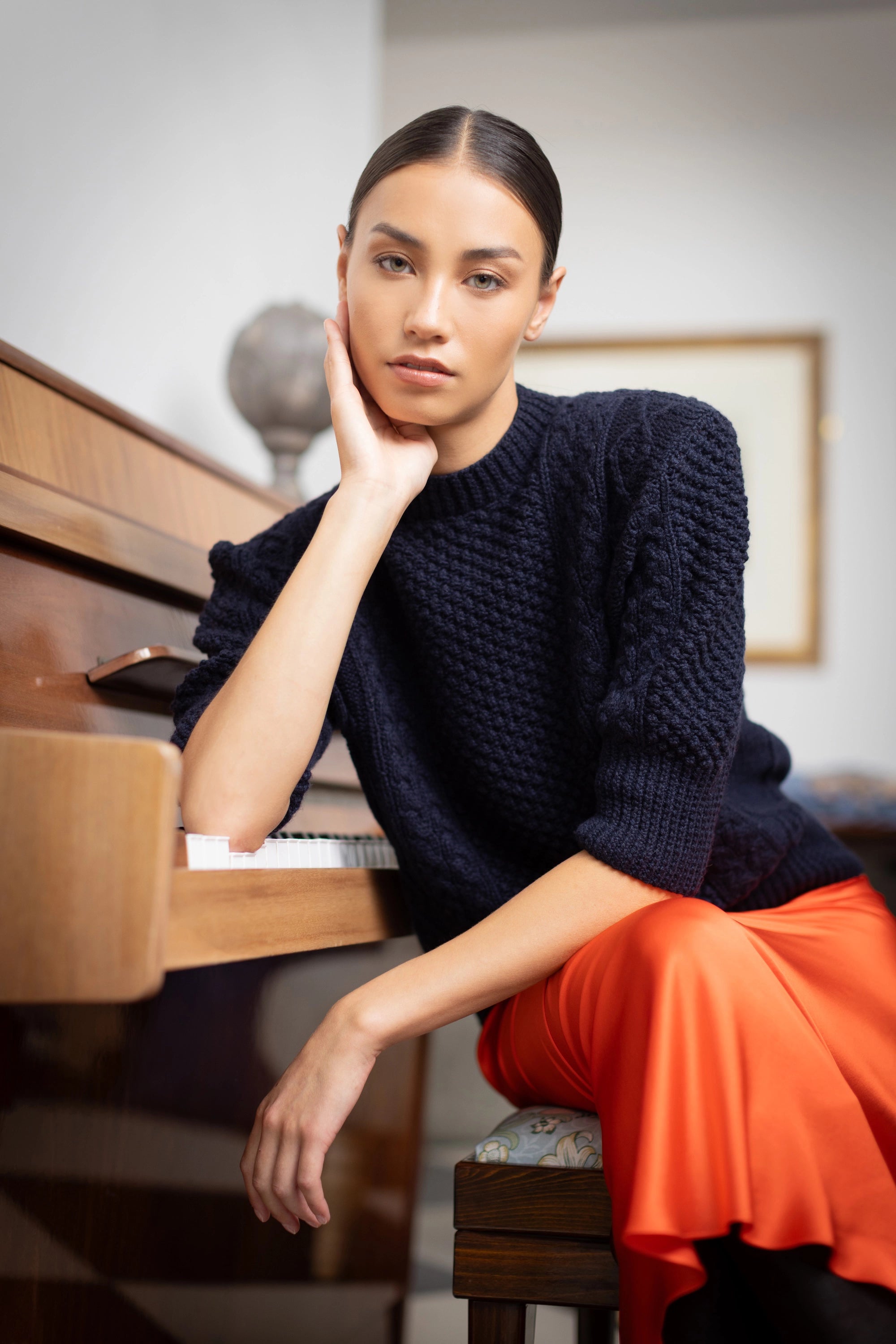 A woman wears a traditional handknit Cashmere Aran Sweater Jumper from Ireland in Navy Blue by Irish luxury cashmere brand Madigan Cashmere