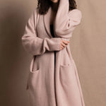 A woman wears a pure 100% cashmere dressing gown or robe in dusty pink