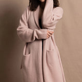 A woman wears a pure 100% cashmere dressing gown or robe in dusty pink