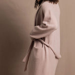 A woman wears a pure 100% cashmere dressing gown or robe in dusty pink