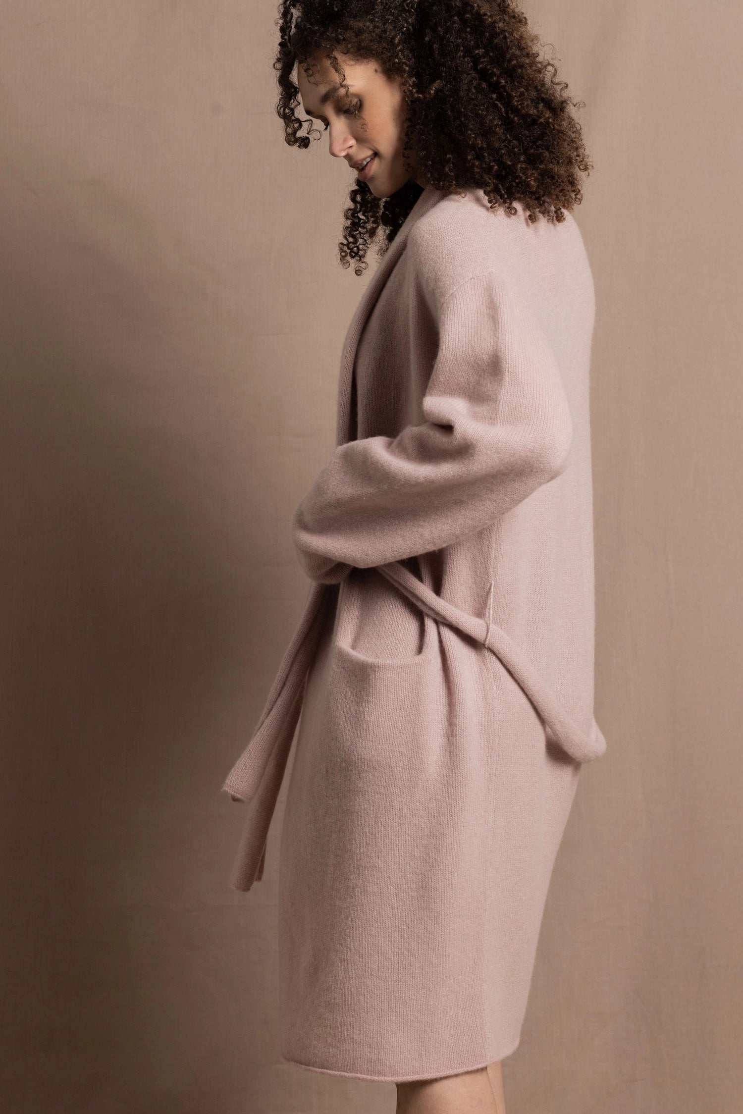A woman wears a pure 100% cashmere dressing gown or robe in dusty pink