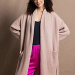 A woman wears a pure 100% cashmere dressing gown or robe in dusty pink with bright shocking pink silk trousers