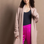 A woman wears a pure 100% cashmere dressing gown or robe in dusty pink with bright shocking pink silk trousers