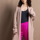 A woman wears a pure 100% cashmere dressing gown or robe in dusty pink with bright shocking pink silk trousers