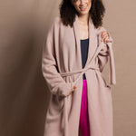 A woman wears a pure 100% cashmere dressing gown or robe in dusty pink with bright shocking pink silk trousers