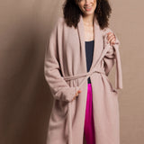 A woman wears a pure 100% cashmere dressing gown or robe in dusty pink with bright shocking pink silk trousers