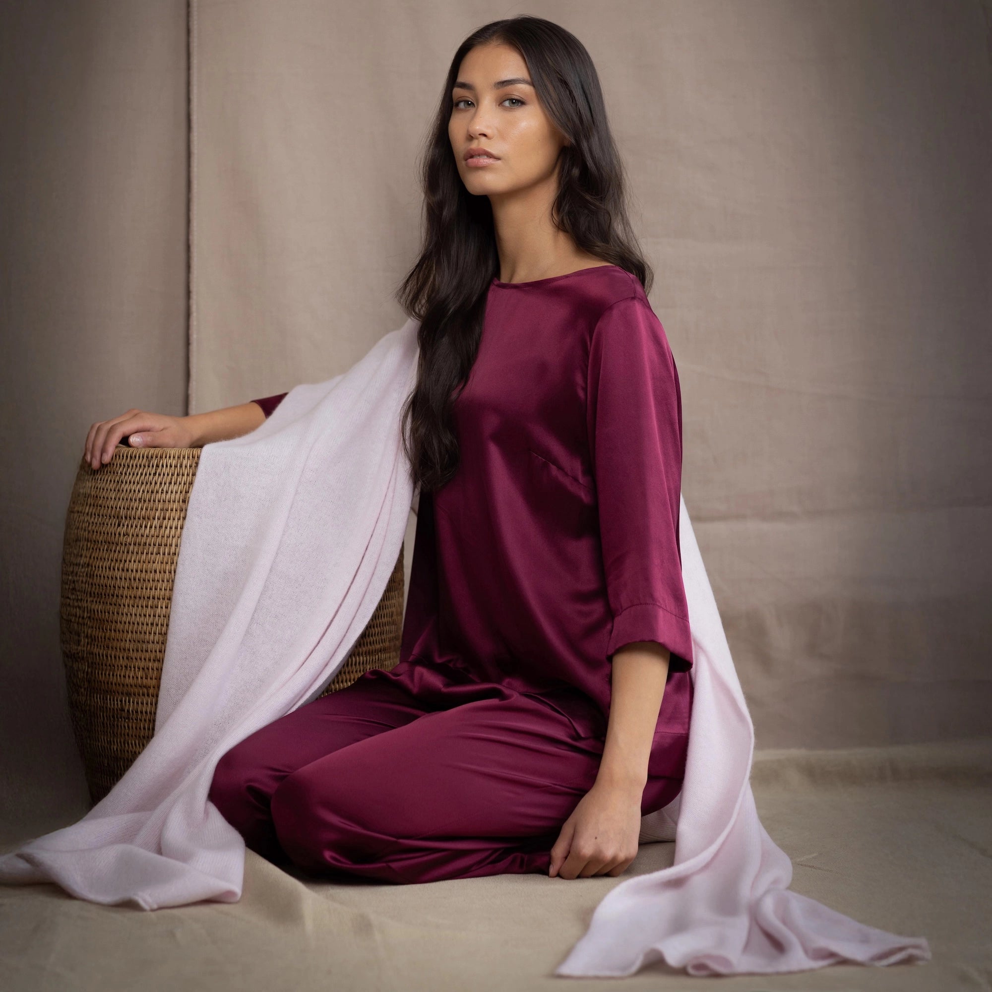 Woman in a burgundy silk top and trousers with a cashmere wrap scarf in pale pink