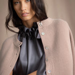 Woman wearing a beige cashmere cardigan with mother of pearl buttons over a grey pewter silk top