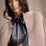 Woman wearing a beige cashmere cardigan with mother of pearl buttons over a grey pewter silk top