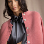 woman wearing a cashmere cardigan  in dusty pink rose with mother of pearl buttons over dark grey silk top and trousers