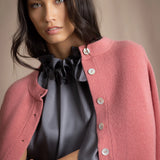 woman wearing a cashmere cardigan  in dusty pink rose with mother of pearl buttons over dark grey silk top and trousers