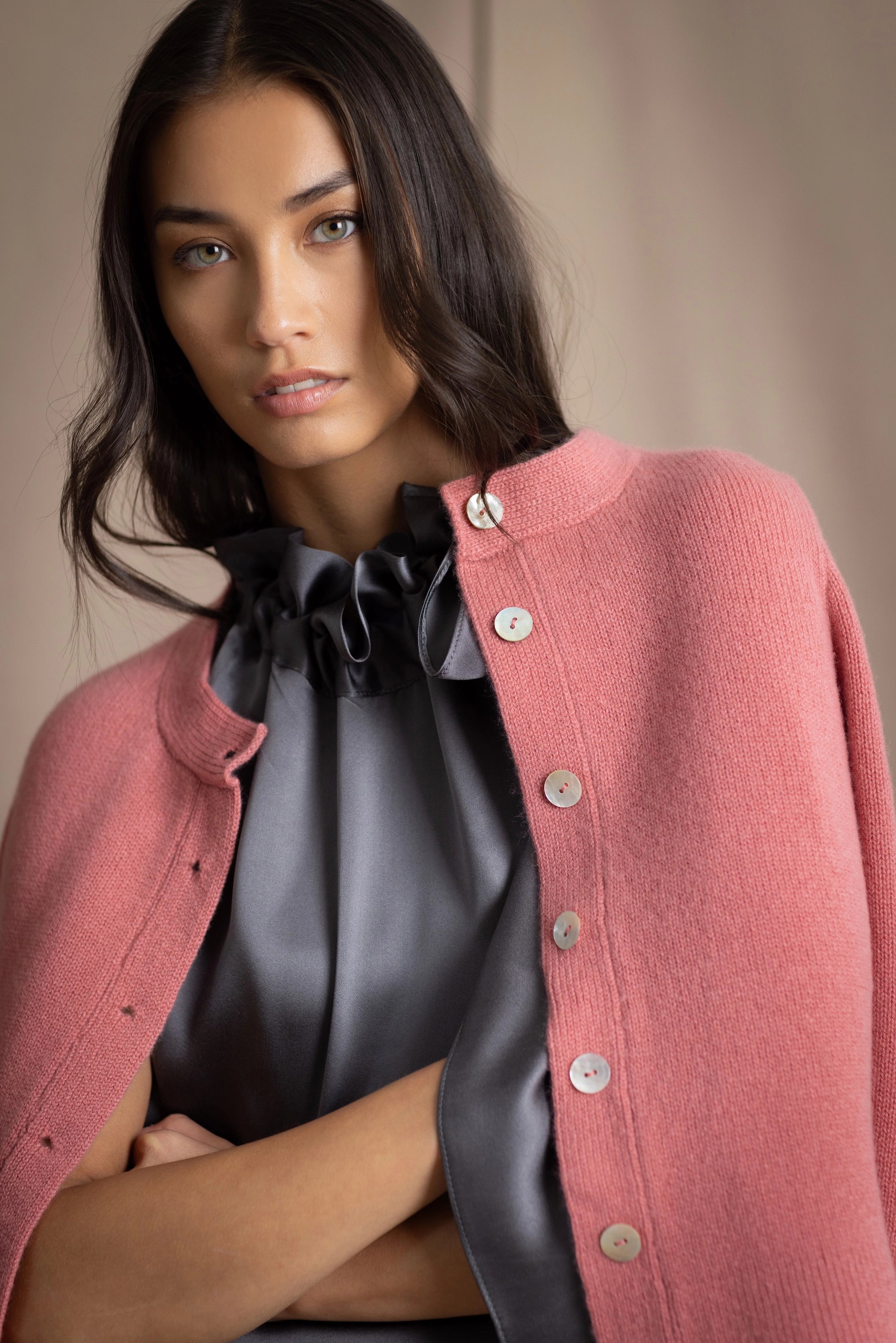 woman wearing a cashmere cardigan  in dusty pink rose with mother of pearl buttons over dark grey silk top and trousers