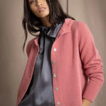 woman wearing a cashmere cardigan with buttons in dusty pink rose colour over dark grey silk top and trousers