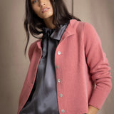 woman wearing a cashmere cardigan with buttons in dusty pink rose colour over dark grey silk top and trousers