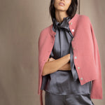 woman wearing a cashmere cardigan with buttons in dusty pink rose colour over dark grey silk top and trousers