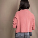 woman wearing a cashmere cardigan  in dusty pink rose with mother of pearl buttons over dark grey silk top and trousers