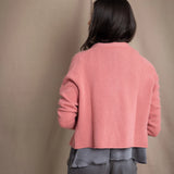 woman wearing a cashmere cardigan  in dusty pink rose with mother of pearl buttons over dark grey silk top and trousers