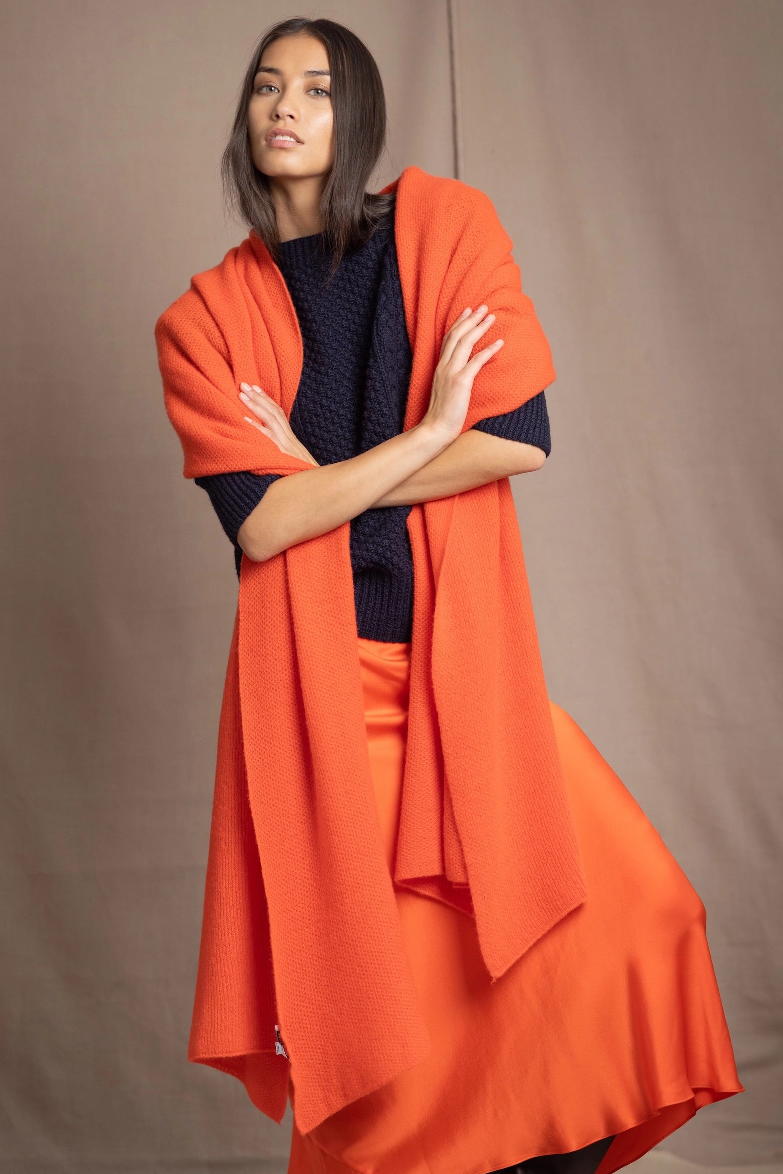 a woman wears an extra large cashmere wrap shawl in bright orange
