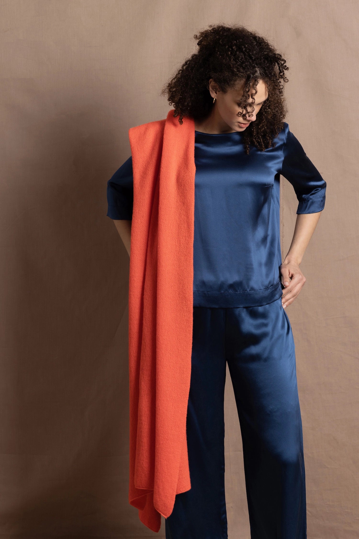 A lady wears a pure silk 3/4 sleeve blouse in teal with matching trousers and large orange cashmere wrap