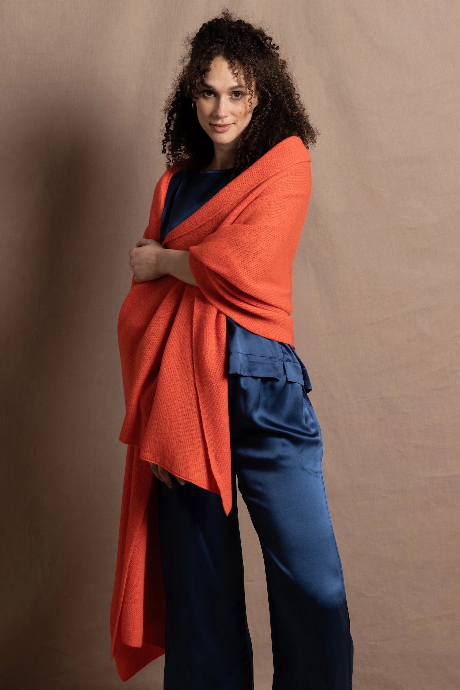A lady wears a pure silk 3/4 sleeve blouse in teal with matching trousers and large orange cashmere wrap