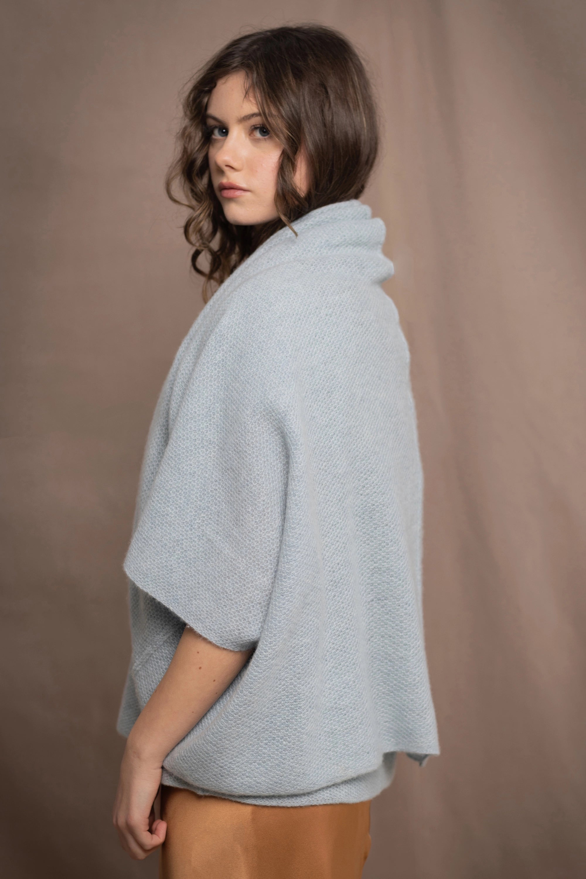 A woman wears a cashmere shawl cardigan in pale blue turquoise colour