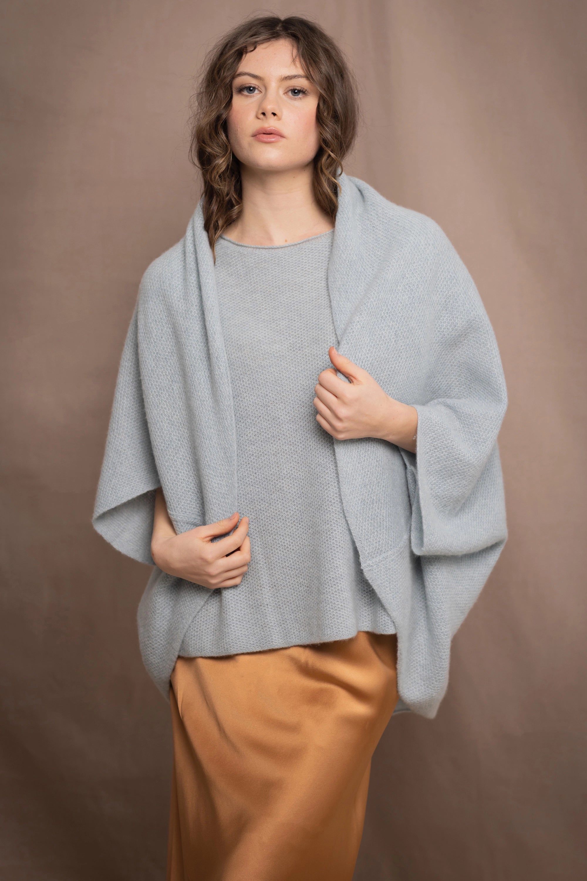 a woman wears a pure 100% cashmere tee sweater and matching cocoon cardigan in pale light blue turquoise over a bronze silk skirt 