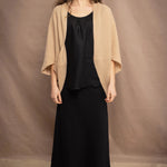 a woman wears a beige cashmere cocoon cardigan with a moss texture  over black linen top and skirt by Irish brand Madigan