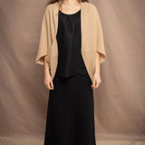 a woman wears a beige cashmere cocoon cardigan with a moss texture  over black linen top and skirt by Irish brand Madigan
