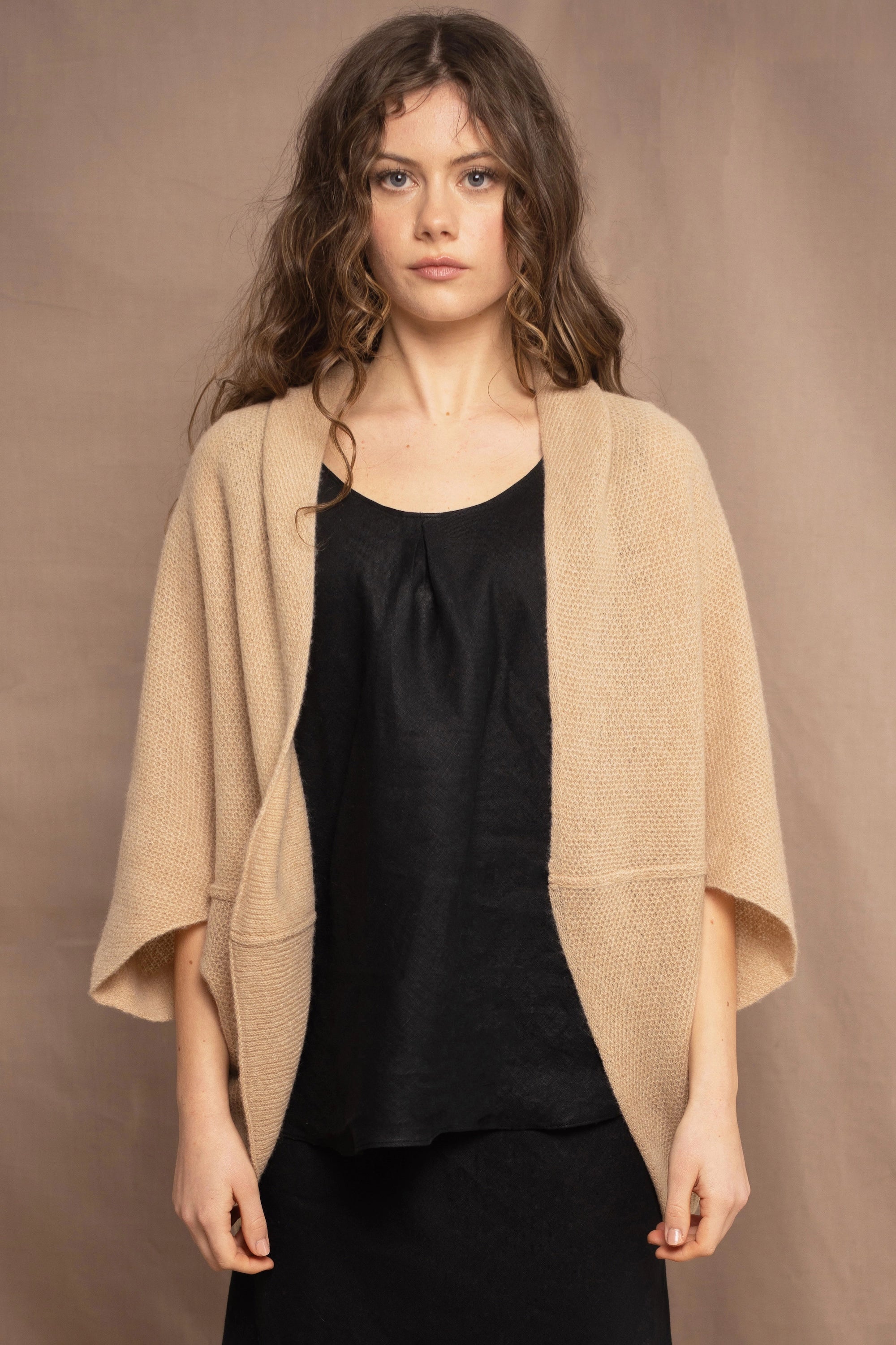 a woman wears a beige cashmere cocoon cardigan with a moss texture by Irish brand Madigan