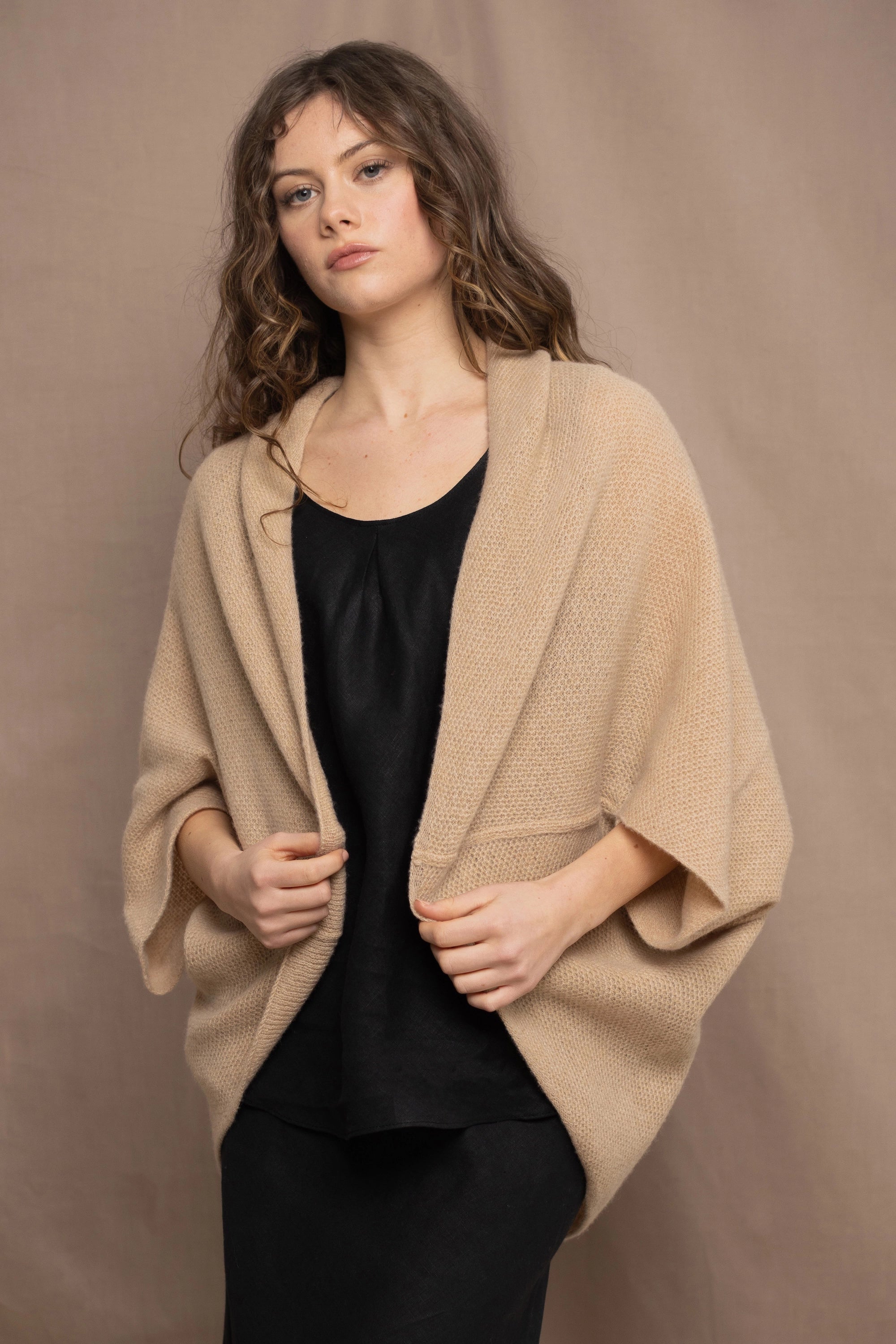 a woman wears a beige cashmere cocoon cardigan with a moss texture by Irish brand Madigan