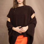 a woman wears a cashmere cocoon cardigan in dark brown with matching tee sweater underneath over a silk skirt in bright orange by Irish brand Madigan